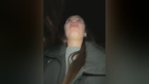 Media: A blurry video of a woman in a dark coat, possibly crying, with her mouth open, standing against a dimly lit background.