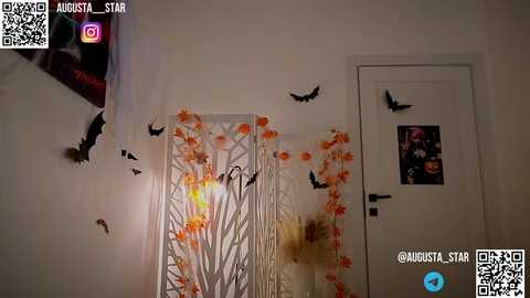 Media: Video of a bedroom with a white door, adorned with orange and black paper cutouts of bats, and a white window with similar cutouts. A QR code and social media icons are in the top left corner.