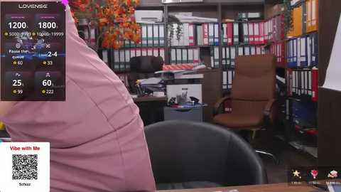 Media: Video of a cluttered office with a large screen showing a VR headset user. The office features bookshelves, a brown leather chair, and a messy desk.