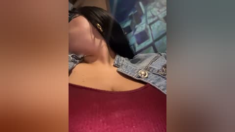 Media: A video of a woman with fair skin and black hair, wearing a red top and denim jacket, lying on a bed with a brick-patterned wall in the background.