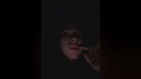 Media: A dimly lit, grainy video shows a close-up of a woman with short, dark hair, her mouth partially open, and her eyes obscured by shadows.