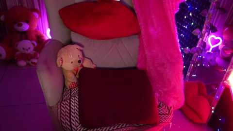 Media: Video of a plush teddy bear in a cozy chair, surrounded by red and purple lights, plush toys, and a festive Christmas tree with glowing ornaments.