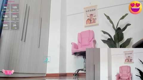 Media: Video of a minimalist room with white walls, a pink office chair, a potted plant, and a light pink poster, all against a modern, light-colored wooden floor.