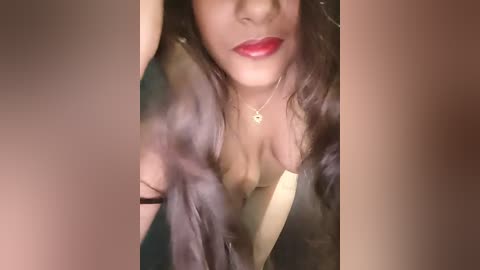 Media: A video shows a woman with medium brown skin, wearing red lipstick, a black dress, and a gold necklace, her long, wavy hair partially obscuring her face.