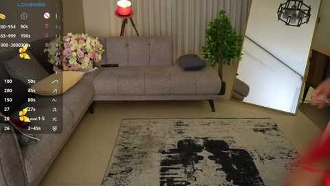 Media: A video of a modern living room with beige couch, grey armchair, floral arrangement, red lamp, and abstract art on a patterned rug.