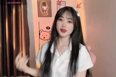 Media: Video of a young Asian woman with long black hair, wearing a white shirt, standing in a dimly lit room with bear-themed decorations and curtains.