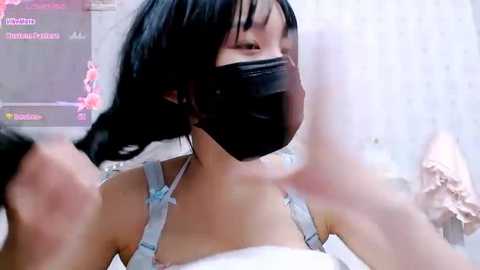 Media: Video of an East Asian woman with black hair, wearing a black mask and light blue lingerie, standing indoors with blurred background.