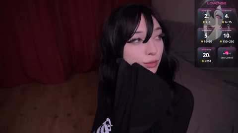 Media: Video of a fair-skinned, young woman with long black hair, wearing a black top, with a digital interface showing streaming stats in the background.