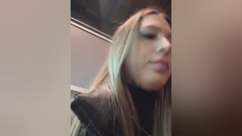 Media: A video of a blonde woman with long hair, wearing a black leather jacket, captured from a low angle, showing her face partially blurred and out of focus.