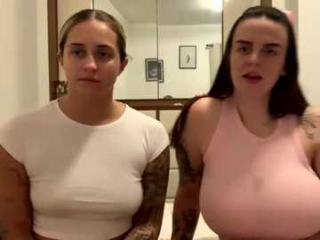 Media: Video of two women with different breast sizes; one with small, the other with large, in tight tops, sitting indoors.