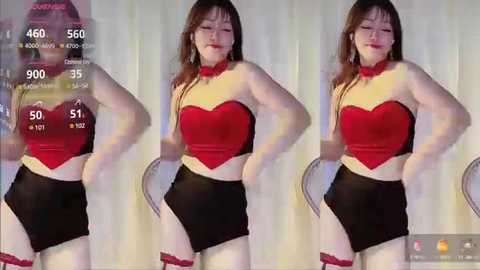 Media: Video of a plus-sized Asian woman with long brown hair, wearing a red and black strapless crop top and black shorts, posing in front of a white curtain.