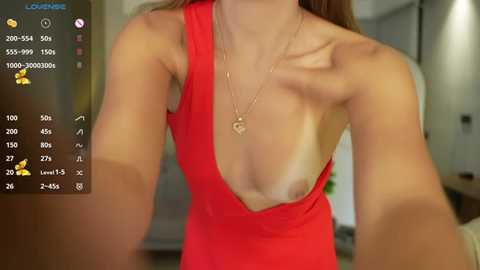 Media: A video of a fair-skinned woman with long brown hair, wearing a low-cut red dress, revealing her breasts. The background shows a blurred living room with a mirror.