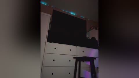 Media: Video of a dimly lit bedroom with a white dresser, black TV, and neon blue lights.