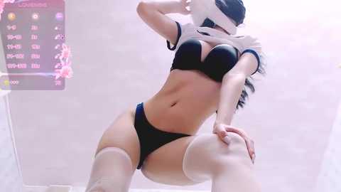 Media: Video of a slender, light-skinned woman in black lingerie, white thigh-high stockings, and a virtual reality headset. She poses provocatively with one knee bent, against a blurred, white background.