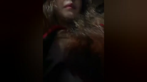 Media: Video of a woman with fair skin, curly brown hair, and red lipstick, wearing a black garment, captured from a low angle, creating a dramatic, moody atmosphere.