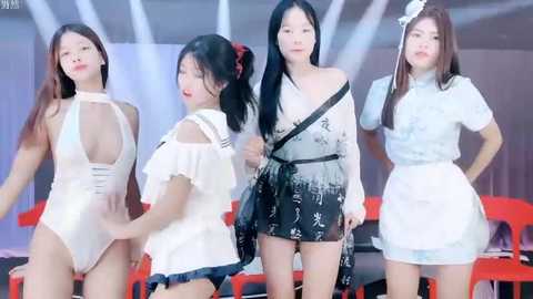 Media: Video of four Asian women in revealing, semi-transparent, white, and black outfits on a stage with red chairs and white curtains.