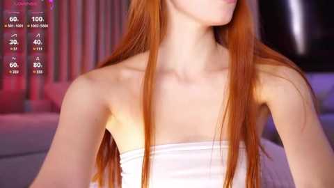 Media: Video of a slender, fair-skinned woman with long, straight red hair, wearing a white strapless top, standing against a blurred, dimly lit background with pink and purple hues.