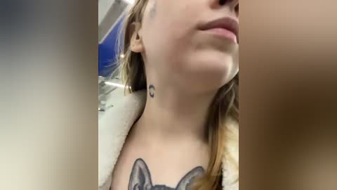 Media: Video of a woman with light skin, brown hair, and a tattoo of a cat's face on her chest, wearing a furry coat.