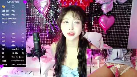 Media: Video of an East Asian woman with long black hair in a pink and black checkered room, wearing a light blue dress and a lace thong, singing into a microphone.