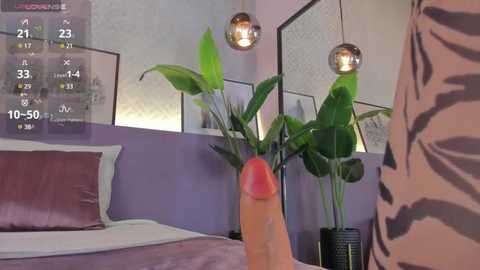 Media: Video of a modern bedroom with a large, erect, circumcised penis in the foreground; a tiger-patterned person's back visible on the right, a bed with purple walls and green plants in the background.