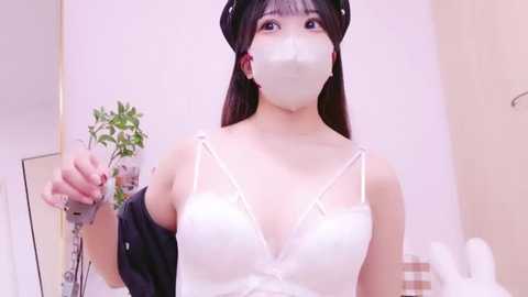 Media: Video of an East Asian woman with light skin, wearing a white lace bra, black headband, and face mask, holding a chainsaw.