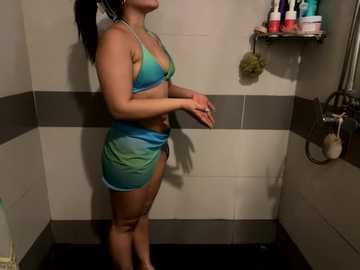 Media: Video of a curvy woman in a teal bikini, standing in a tiled bathroom with a gray and white striped wall.