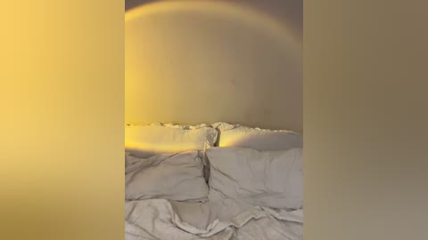 Media: A video of a dimly lit bedroom with a sunbeam streaming through a window, illuminating white bedding and creating a warm, golden glow on the wall. The scene is cozy and serene, emphasizing natural light.