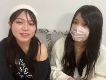 Media: Video of two East Asian women with long black hair, wearing masks, one in a white hat, black top, and grey background, the other in a white sweater.