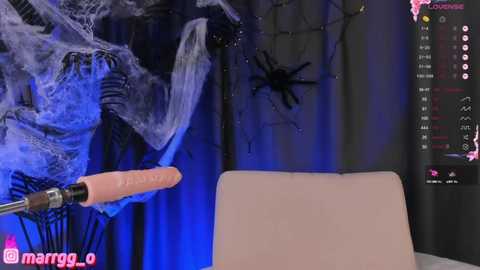 Media: A video of a person in a dark costume with a spider web, holding a realistic spider model against a blue-lit background.