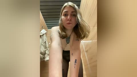 Media: Video of a young, pale-skinned, blonde woman with shoulder-length hair, topless, leaning forward in a wooden box with a grey blanket and a paper towel visible.