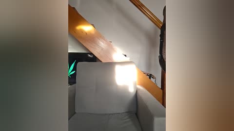 Media: Video of a dimly lit attic space with a wooden staircase, white chair, and a bright light source casting shadows on the walls.