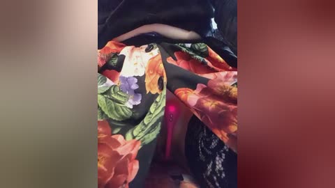 Media: A video showing a person wearing a vibrant floral kimono with orange, green, and purple hues, partially covering a black lace garment. The setting appears to be indoors, with the person sitting.