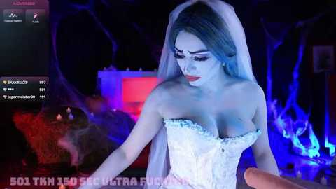 Media: Video of a pale-skinned woman in a white corset and veil, with dramatic makeup, standing in a dark, fiery room. Text overlay: \"B01 THM2 - 5% UBER FUCK ME.\