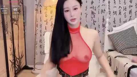 Media: Video of an Asian woman with long black hair, wearing a revealing red halter top that reveals her breasts, standing in a room with Japanese calligraphy wallpaper and white furniture.