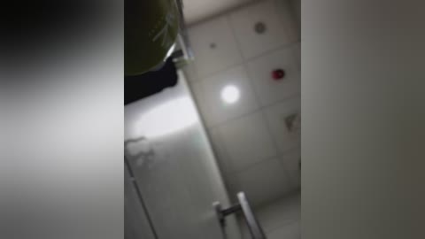 Media: A blurred video of a bathroom, featuring a white tiled wall, a metallic faucet, and a small, bright light source. The image is slightly out of focus, emphasizing a dim and slightly dark atmosphere.