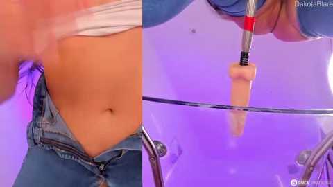 Media: Video of a woman's lower torso and midsection, partially undressed, wearing a white tank top and blue jeans. She holds a realistic, tan-colored dildo against a purple-lit glass surface, showcasing a close-up of her exposed stomach and the dildo's texture.