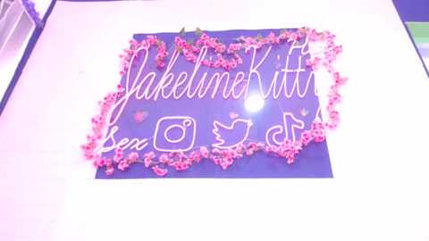 Media: Video of a blue backdrop decorated with pink flowers and \"Jakenekitten\" in cursive writing.