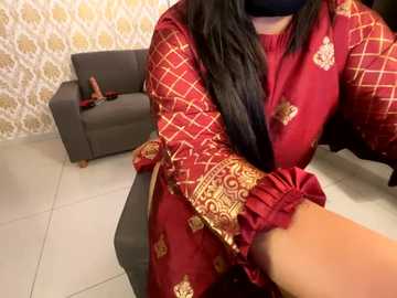 Media: A video of a person with long black hair, wearing a red dress with gold patterns, sitting on a gray sofa. The background features a patterned white and gold wallpaper.