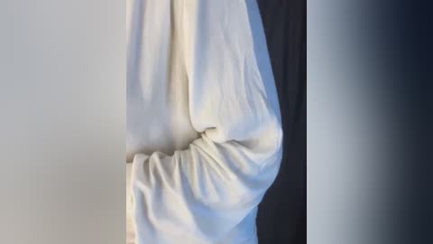 Media: Video of a person's hand, partially obscured by a white towel, wrapped around the wrist, with a dark background. The towel's texture appears soft and slightly crumpled.