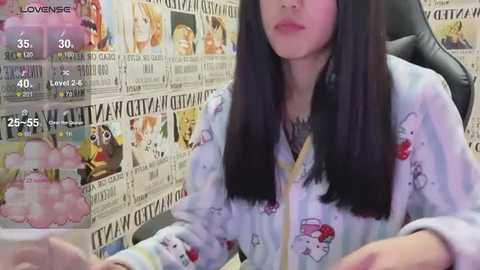 Media: Video of an Asian woman with long black hair, wearing a Hello Kitty pajama set, sitting in a chair surrounded by newspaper articles.