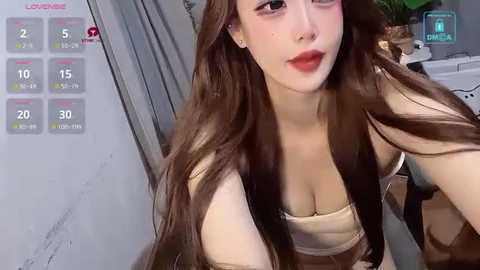 Media: A video of a young Asian woman with long brown hair, wearing a beige top, and makeup. She's indoors, possibly in a bathroom, with a calendar showing daily water intake.