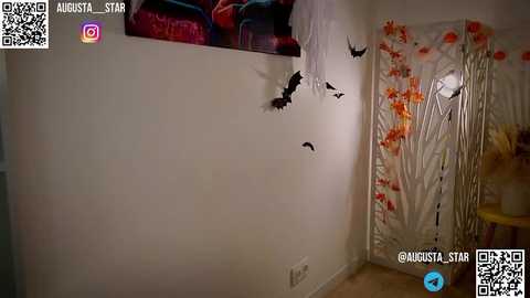 Media: Video of a bedroom wall adorned with black bats and a QR code. Background features a colorful floral curtain and a bed with red and blue pillows.