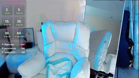 Media: A video of a white leather recliner with a blue cushion, set in a modern room with a mirror, TV, and blue curtains.