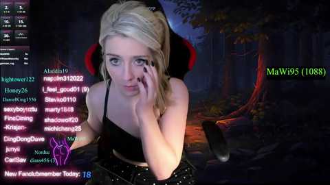 Media: Video of a blonde woman with a pale complexion, wearing a black tank top, sitting on a gaming chair, looking distressed. Background features a dark, forested landscape with a fire.