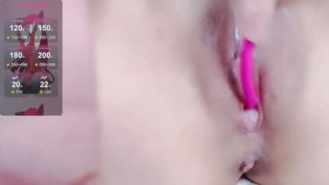 Media: A close-up video of a woman's vulva, displaying pink vaginal lips. The background includes a blurred image of a red-haired woman in a black outfit, overlaid with a digital display showing temperature and humidity readings.