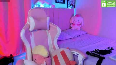 Media: Video of a pink gaming chair, a plush dog toy, and a desk lamp in a bedroom with purple and pink lights.