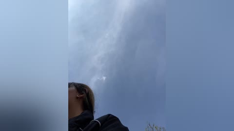 Media: Video of a woman with blonde hair, wearing a black jacket, standing in a smoky, hazy environment. Dense smoke clouds obscure the background, creating a moody, surreal atmosphere.