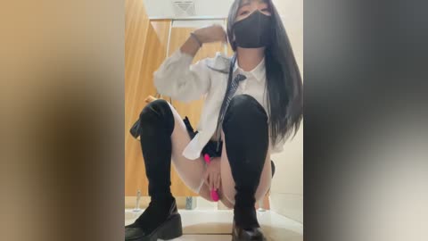 Media: Video of a woman in a bathroom, crouched, wearing a white shirt, black thigh-high socks, and black shoes, with long black hair and a face mask.