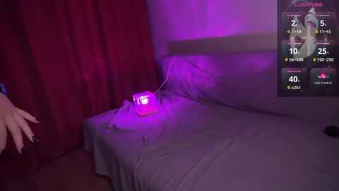 Media: Video of a dimly-lit bedroom with a bed covered in white sheets, a glowing red lightbulb on the pillow, and a digital screen displaying a timer and a clock.