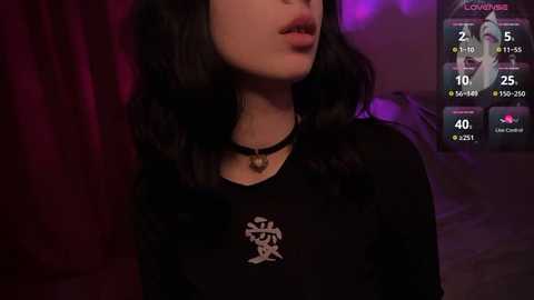 Media: Video of a young woman with long black hair, wearing a black shirt with Chinese characters, a black choker, and a red light in the background.